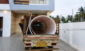 Construction material delivery with large pipe being unloaded from a truck at a residential site, project management by Walls Asia in Hyderabad
